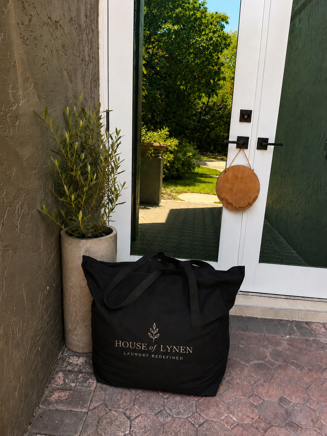 Branded black House of Lynen laundry bag waiting at a client's front door